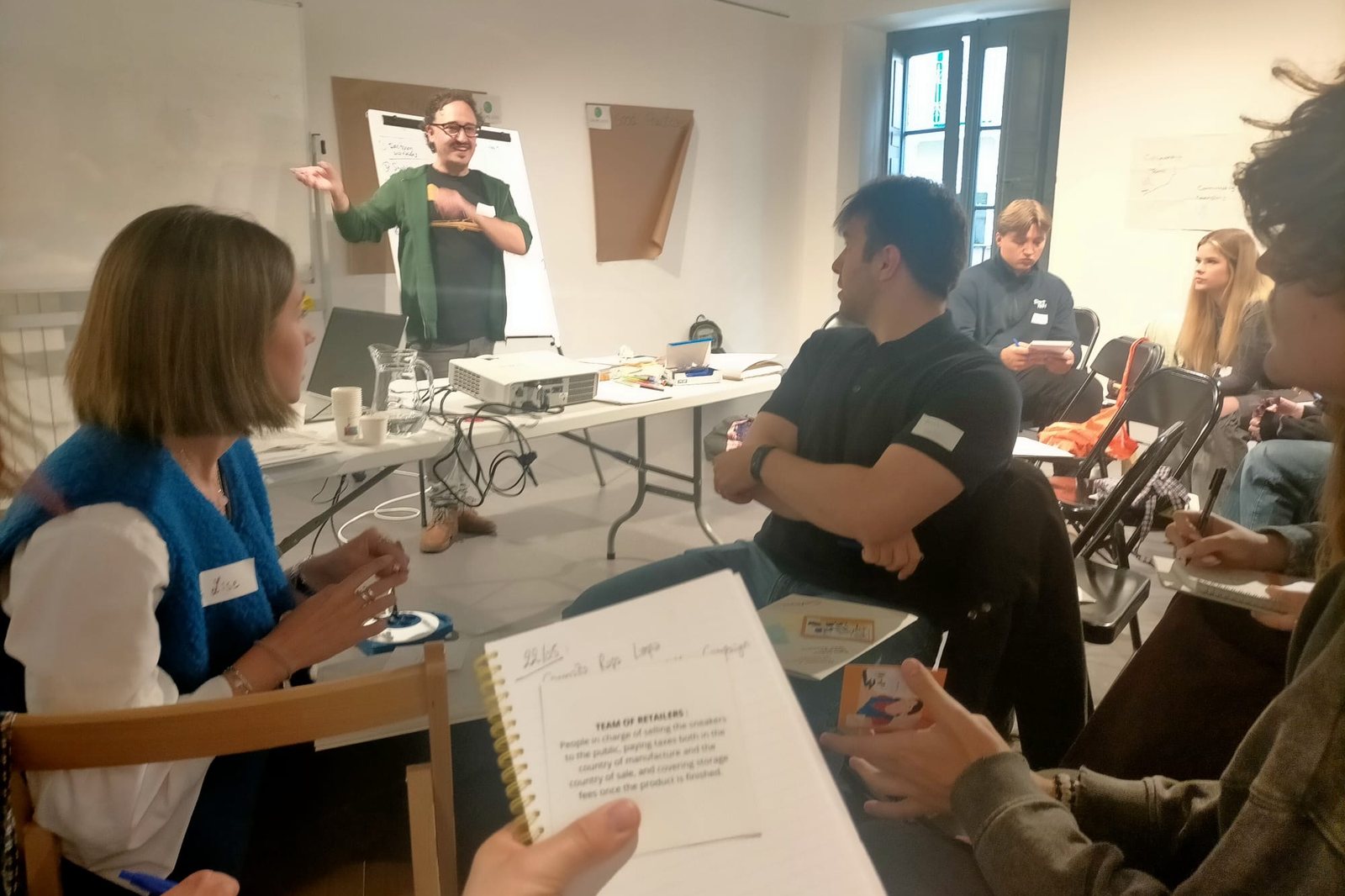 A facilitator speaks to participants seated in a circle during a workshop in Pamplona
