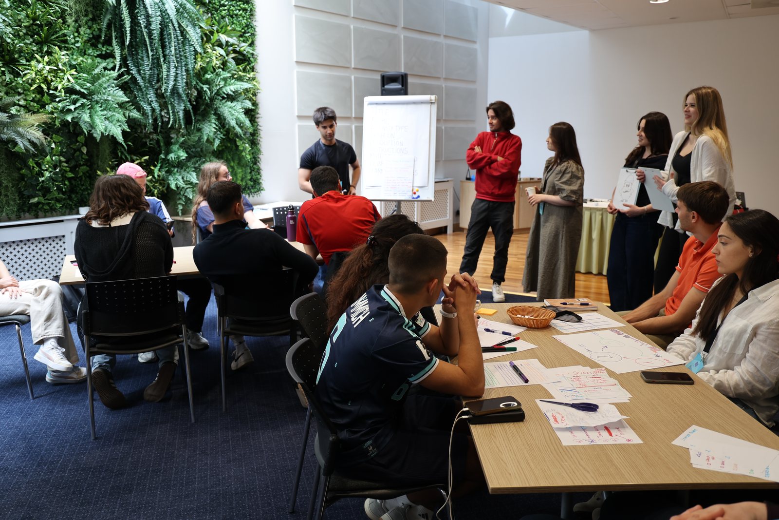 A team presents its activity to participants seated around tables