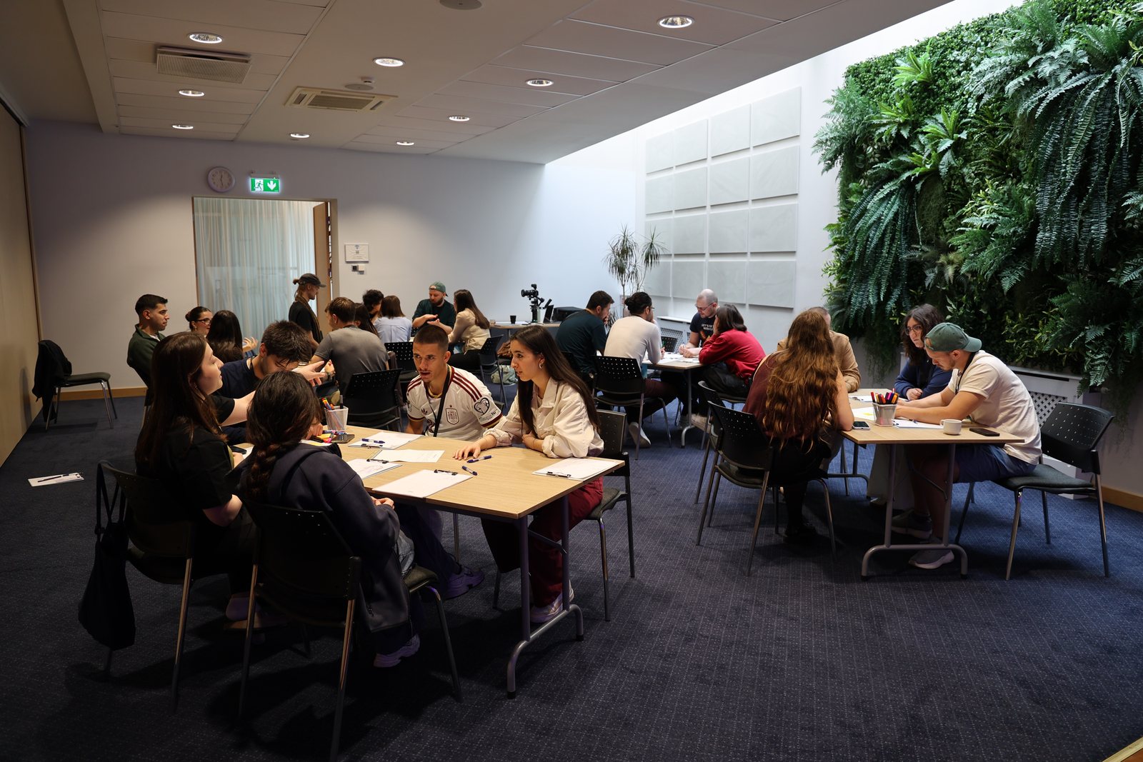Participants work in small groups at tables in the training room